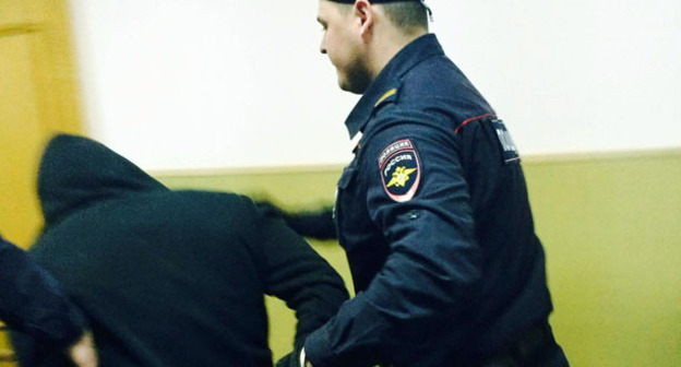 Сотрудник правоохранительных органов ведет обвиняемого по коридору Басманного районного суда Москвы. 6 апреля 2015 г. Фото корреспондента "Кавказского узла"