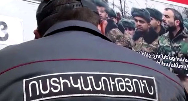 Сотрудник полиции на фоне плаката активисто "Учредительного парламента". Фото: RFE/RL 