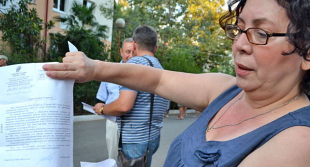 Жительница микрорайона "Гагаринский" показывает петицию с просьбой не допустить строительство высотного здания на улице Новоселов. Сочи, 25 июля 2015 г. Фото Светланы Кравченко для "Кавказского узла"