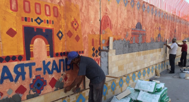 Строители покрывают плиткой стену с рисунками Заиры Панаевой. Дербент, 9 сентября 2015 года. Фото: Сергей Расулов, Facebook.com