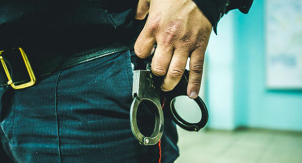 Сотрудник правоохранительных органов с наручниками. Фото: Денис Яковлев / Югополис