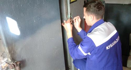 Сотрудник "Кубаньэнерго" взламывает замок на распределительном электрощите на внутридомовом оборудовании. Фото Светланы Кравченко для "Кавказского узла"