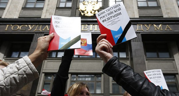 Молодые люди держат в руках Конституцию России на фоне здания Госдумы. Фото: REUTERS/Sergei Karpukhin