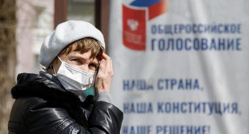 Женщина в защитной маске на остановке общественного транспорта в Ставрополе возле плаката о голосовании по конституционным изменениям. Фото: REUTERS/Eduard Korniyenko