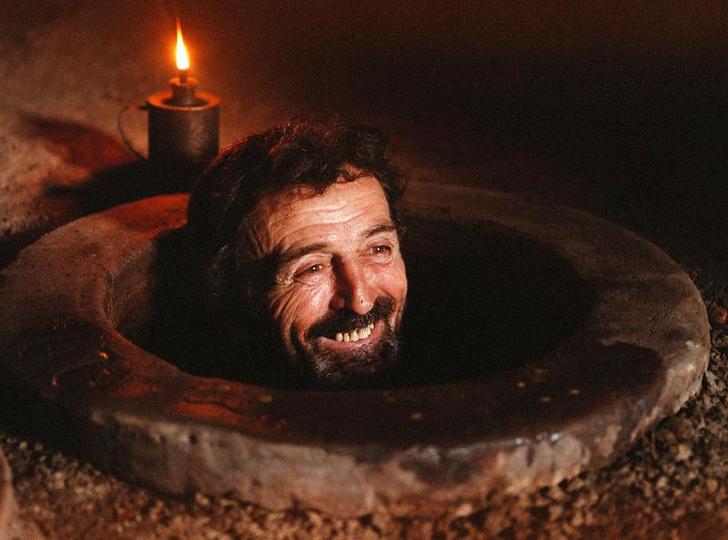 Грузинский фермер Георгий Гвиниашвили улыбается, осматривая огромный 500-литровый кувшин в подвале своего дома в селе Ахашени,примерно в 120 км к востоку от Тбилиси 20 сентября2001 года. Фото: REUTERS/David Mdzinarishvili