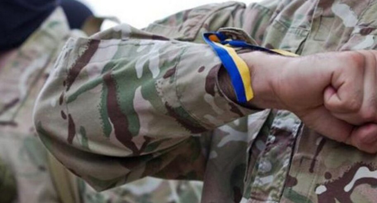 Ленточка с цветами украинского флага на запястье военного. Фото: https://www.newsgeorgia.ge/тела-еще-двух-погибших-в-украине-добро/ Ленточка с цветами украинского флага на запястье военного. Фото: https://www.newsgeorgia.ge/тела-еще-двух-погибших-в-украине-добро/