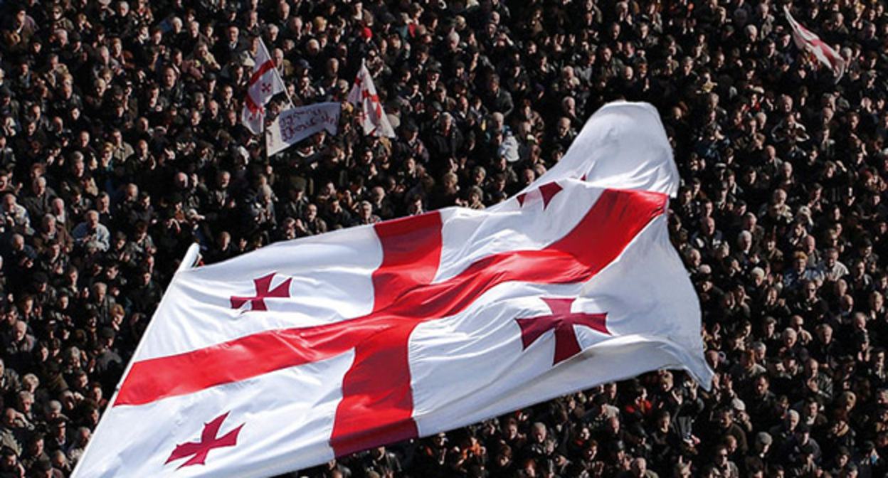 Грузинский флаг на фоне людей. Фото: https://www.newsru.com/world/23nov2012/revolution.html