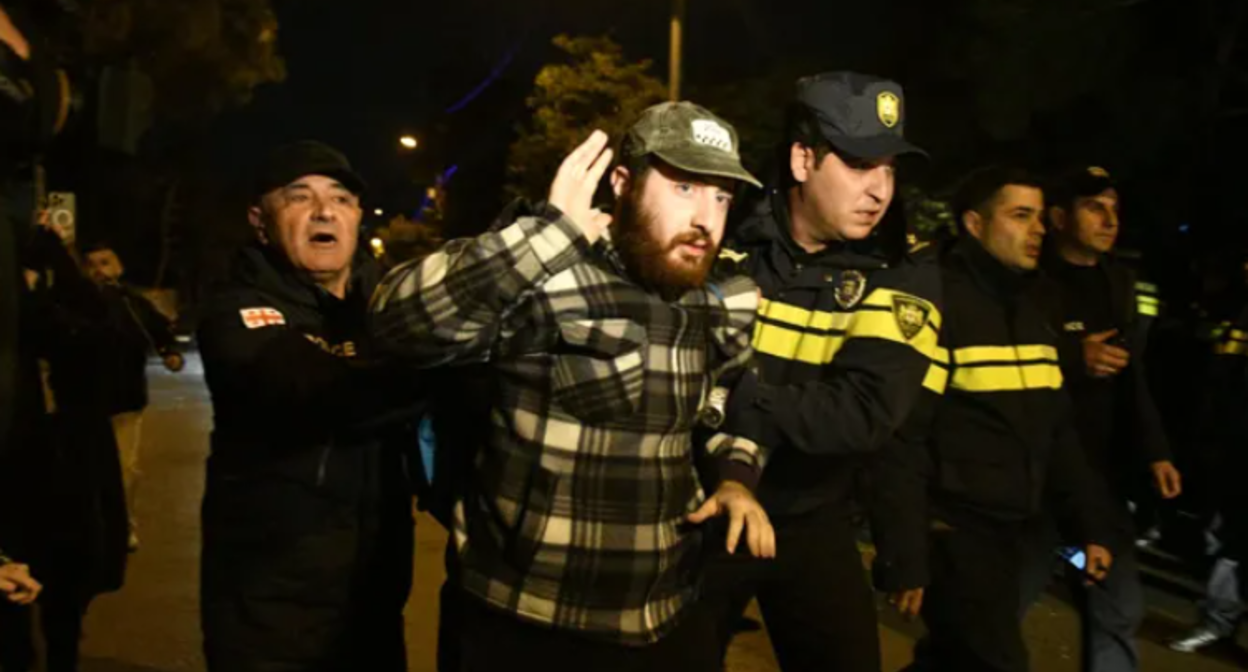 Задержание участника шествия в Тбилиси. Скриншот фото "Интерпрессньюс" от 19.11.25, https://www.interpressnews.ge/ka/article/855075-policiam-mate-devizis-mxardamcheri-msvlelobis-kidev-ramdenime-monacile-daakava