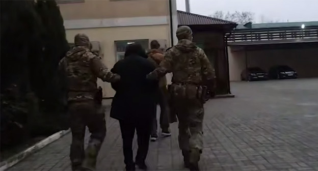 Сотрудники правоохранительных органов сопровождают Изи Алиева. 28 ноября 2025 г. Скриншот видео https://t.me/kommersant/96338