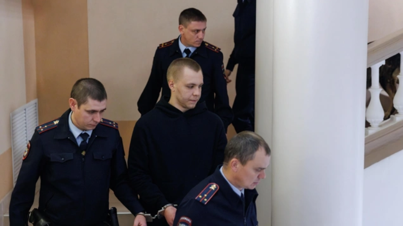 Никита Журавель в окружении силовиков. Скриншот фото Алексея Волхонского/V1, https://v1.ru/text/criminal/2025/10/29/76097063/.