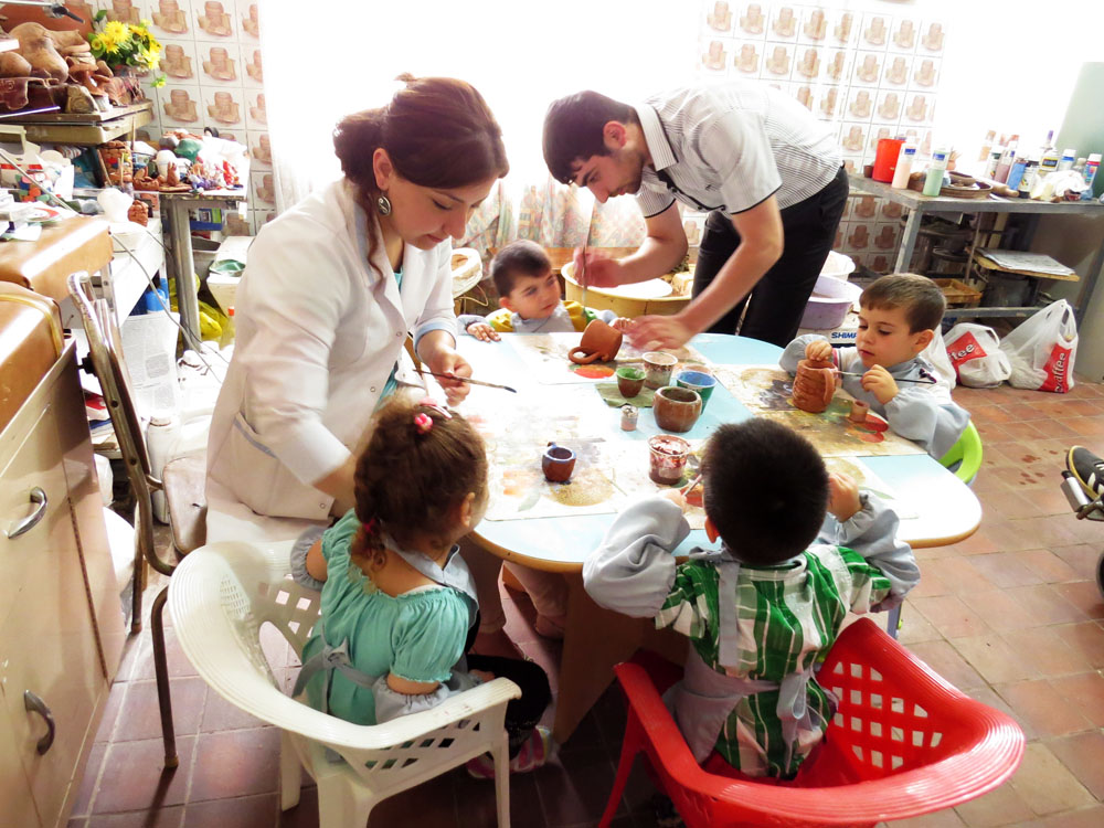 Психолог центра Лусине и Сероб показывают детям как раскрашивать игрушкию