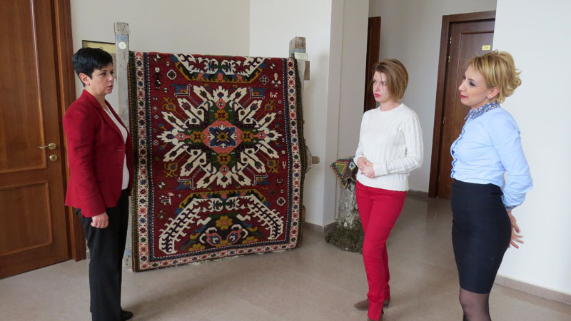 Министр Нарине Агабалян (крайняя слева) с корреспондентом первого канала (Армения), журналистом Мери Давтян и пресс-секретарём министерства культуры НКР Цовинаром Бархударян рядом со старинным ковром.